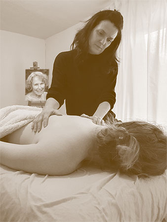 Steffi Krenz behandelt eine Klientin, die auf einer Massageliege liegt. Im Hintergrund ist ein Foto von Marion Rosen.